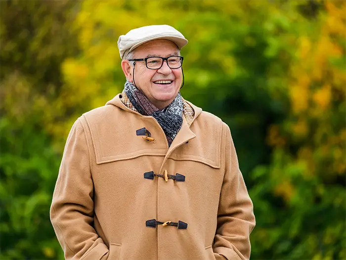 Smiling senior man wearing glasses outdoors in fall