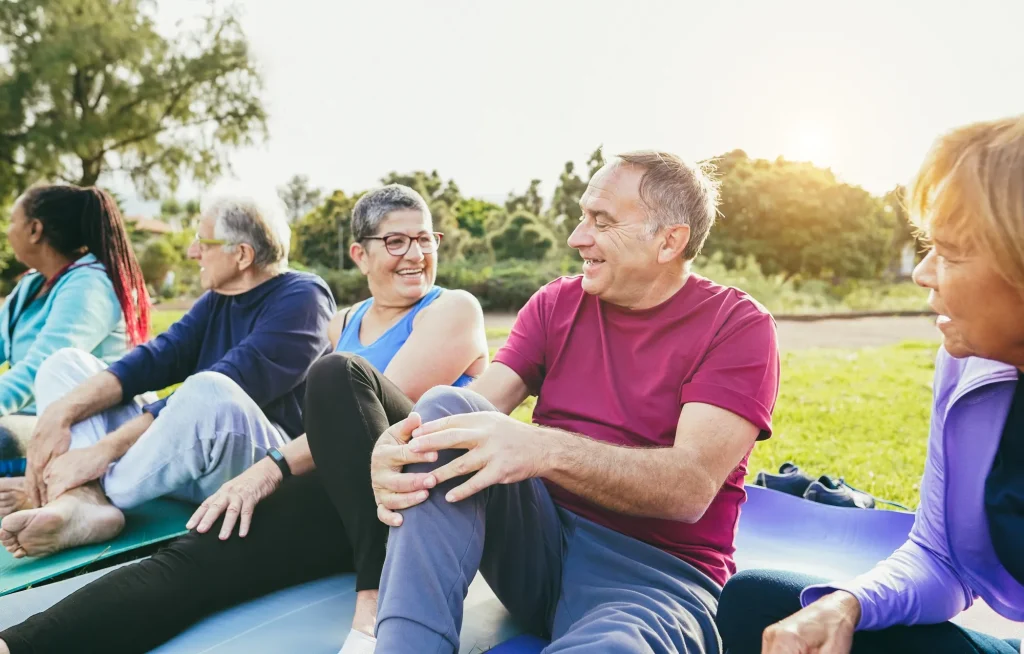 senior friends stretching for exercise and smiling while sitting on the ground