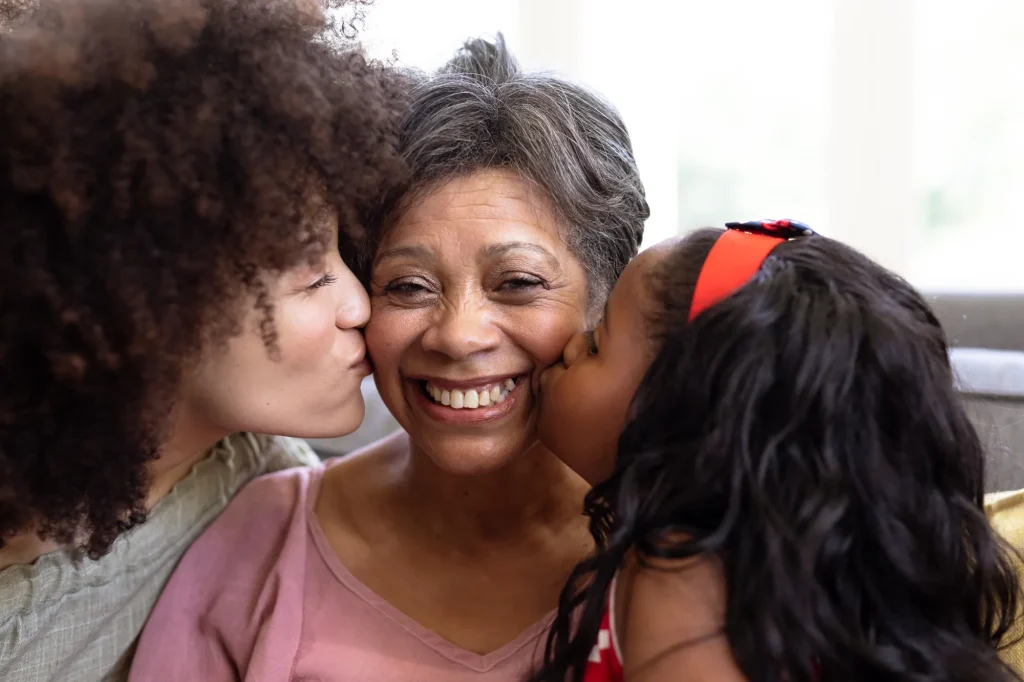 Grandmother smiling while receiving affectionate hugs from family members at home